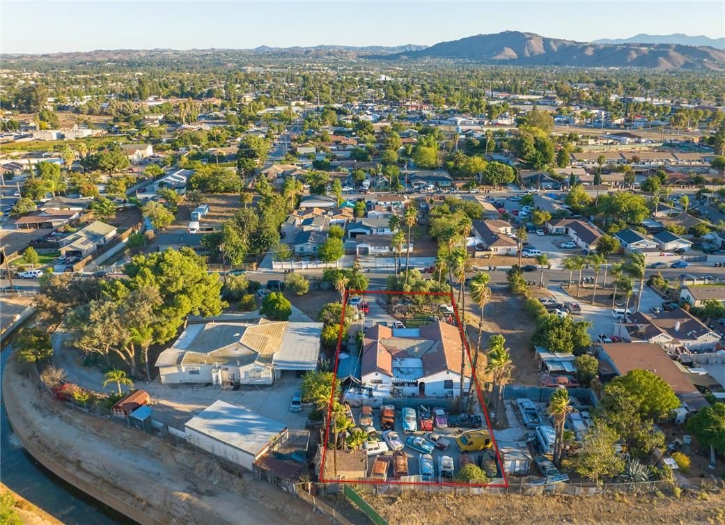 Drone view of a Southern California neighborhood of single-family and small multifamily homes with mountains in the distance